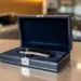 Luxuriöse Geschenkbox mit Autoschlüssel-Anhänger in marineblauem Samt auf Autohaus-Tresen, warme Showroom-Beleuchtung
