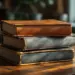 Stapel abgenutzter Büroordner mit Lederstruktur und geprägten Details auf modernem Schreibtisch im warmen Bürolicht