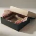 Leicht geöffnete Premium-Geschenkbox mit zerknittertem Seidenpapier und leerer Produktkavität, die auf einen Verpackungsfehler hinweist.
