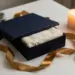 Geöffnete Premium-Firmengeschenkbox mit goldener Schleife, Tannenzweigen und Seidenpapier im weihnachtlichen Kerzenlicht.