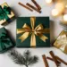 Elegante Firmengeschenkboxen in Tannengrün und Mattgold mit Satinschleifen, dekoriert mit Kiefernzweigen und Zimtstangen auf weißem Untergrund.