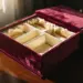 Geöffnete burgunderfarbene Samtgeschenkbox mit cremefarbenen Seidenfächern auf polierter Holzoberfläche bei natürlichem Licht