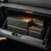 Elegante Geschenkboxen in schwarz und gold perfekt verstaut im geöffneten Handschuhfach eines Autos