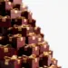 Hoch gestapelte Reihen eleganter Geschenkboxen in Burgunderrot und Gold mit Schleifenbögen, flache Schärfentiefe, warmes Studiolicth.