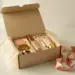 Geöffnete Influencer-PR-Box mit Premium-Kosmetikprodukten in Seidenpapier, goldenen Akzenten und rosa Schleife auf weißem Untergrund.