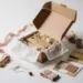 Geöffnete Influencer-Geschenkbox mit Seidenpapier und Premium-Produkt, umgeben von Schleifenresten auf weißer Studiofläche.