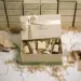 Aufgeschnittene Influencer-Geschenkbox mit goldener Schleife und Premium-Produktproben, umgeben von Seidenpapier auf weißer Fläche, gestapelte Boxen im Hintergrund.