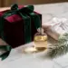 Luxuriöse Weihnachtsgeschenkbox mit Samtband, Glasflakon und Tannenzweig auf weißem Marmor im Kerzenlicht.