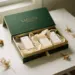 Luxuriöse Geschenkbox mit leicht geöffnetem Deckel, Produktproben in Seidenpapier, getrocknete Botanicals, mattes Gold und Waldgrün.