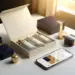 Geöffnete Premium-Geschenkbox mit matten Texturen in Creme, Marineblau und Gold, umgeben von Produktverpackungen und Smartphone mit Engagement-Diagrammen.