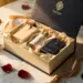 Geöffnete Luxus-Geschenkbox mit Produktproben in Seidenpapier, Rosenblättern und Goldakzenten auf Marmor im warmen Licht.