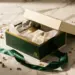 Luxuriöse Geschenkbox mit Premium-Produktproben in Seidenpapier, Satinband und getrockneten Blumen auf weißem Marmor.