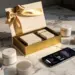 Geöffnete Luxus-Geschenkbox mit elegantem Band auf Marmoroberfläche, umgeben von Produktproben und Smartphone mit Engagement-Metriken.
