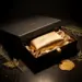 Luxuriöse matte Geschenkbox mit geöffnetem Deckel, seidengefüttertem Innenraum und goldenem Wachssiegel auf dunkler Walnussoberfläche.