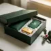 Luxuriöse Geschenkbox mit matter Oberfläche, halb geöffnet, mit edlem Marken-Merchandise und Seidenpapier, dekoriert mit Stechpalmenzweig.