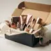 Aufgeklappte Influencer-Geschenkbox mit Kosmetikprodukten, Seidenpapier und Rosegold-Band auf weißem Untergrund.