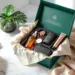 Luxuriöse smaragdgrüne PR-Box mit Lifestyle-Produkten auf Marmortisch, enthält Hautpflege, Tech-Zubehör und Wellness-Artikel
