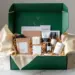 Luxuriöse smaragdgrüne PR-Box mit Goldakzenten auf Marmortisch, gefüllt mit Lifestyle-Produkten in champagnerfarbenen Einsätzen