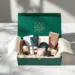 Luxuriöse smaragdgrüne PR-Box mit Goldakzenten auf Marmortisch, gefüllt mit Hautpflege, Tech-Zubehör und Kaffee