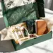 Luxuriöse PR-Box in Smaragdgrün mit Golddetails enthält Hautpflege, Kaffee, Kopfhörer und Schokolade auf weißem Tisch