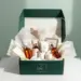 Geöffnete Premium-PR-Box in waldgrün mit roségoldenen Akzenten, gefüllt mit Hautpflege, Tech-Zubehör und Lifestyle-Produkten
