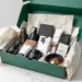 Luxuriöse smaragdgrüne PR-Box mit Premium-Lifestyle-Produkten, Hautpflege und Tech-Zubehör auf weißem Studiotisch