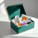 Geöffnete Luxus-PR-Box in Smaragdgrün mit schlecht arrangierten Beauty- und Tech-Produkten auf weißem Studiotisch