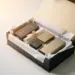 Geöffnete Premium-PR-Geschenkbox mit Seidenpapier, Schleife und Produktproben in Gold- und Anthrazittönen auf weißem Untergrund.