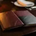 Aufgeklappte Kunstleder-Speisekarte auf dunklem Holztisch eines Hotelrestaurants, beleuchtet von warmem Kerzenschein.