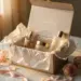 Geöffnete Geschenkbox mit Luxuskosmetik auf Marmor, umgeben von Seidenpapier, Rosenblüten und goldener Schleife im warmen Abendlicht.
