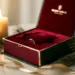 Geöffnete Luxus-Weihnachtsgeschenkbox mit samtgefüttertem Inlay, Tannenzweigen und Goldband im warmen Kerzenlicht.