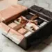 Geöffnete Influencer-Unboxing-Box auf Marmor mit Markenseidenpapier, Schleife und Premium-Produktproben in Rosegold und Anthrazit.
