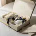 Geöffnete Luxus-Geschenkbox mit Seidenpapier, Premium-Produktproben und handgeschriebenem Kärtchen auf weißer Fläche.