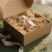Nachhaltiges Influencer-Unboxing-Geschenkset in Kraftpapier-Füllung, Leinenband und getrockneten Botanicals in mattem erdtonfarbenen Karton.