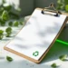 Hochwertiges Klemmbrett mit Recycling-Symbolen und umweltfreundlichen Materialien auf weißer Oberfläche