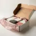 Geöffnete Onboarding-Box mit unordentlichem Seidenpapier, unausgewogener Produktanordnung und strukturellen Mängeln im Studio-Licht.