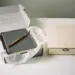 Geöffnete Onboarding-Willkommensbox mit zerknittertem Notizbuch und unordentlichem Inhalt neben einer elegant verpackten geschlossenen Box.
