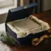 Geöffnete Premium-Geschenkbox mit Magnetdeckel, Seidenpapier und Tannenzweig auf dunklem Eichenholzschreibtisch, goldenes Band, weiches Fensterlicht.