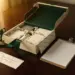 Geöffnete Premium-Geschenkbox mit Produktmustern in Markenpapier, handgeschriebenem Versandetikett und Checkliste auf poliertem Holzschreibtisch im goldenen Nachmittagslicht.