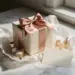 Premium-Geschenkbox mit Satinschleife, handgeschriebener Karte und Produktproben auf weißem Marmor in Roségold- und Elfenbeintönen.