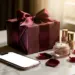 Luxuriöse Geschenkbox mit Satinband, Smartphone, Rosenblättern und Produktproben auf Marmor in warmen Goldtönen.