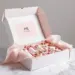 Luxuriöse weiße PR-Box mit Rosé-Gold-Akzenten und Hautpflege-Produkten in rosa Schaumstoff-Einlagen auf Marmortisch