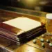 Ledergebundene Speisekarten auf rustikalem Holztresen einer Brauerei, aufgeklappt neben Bierglas und Hopfendolden, warmes Bernsteinlicht.