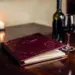 Aufgeschlagene Leder-Speisekarte auf poliertem Restauranttisch mit Weinflasche, gefülltem Glas und Kerzenschein.