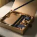 Premium-Onboarding-Box auf modernem Schreibtisch geöffnet, mit Notizbuch, Stift und Willkommensgeschenken in Seidenpapier, champagner- und marineblau.