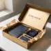 Geöffnete Onboarding-Box mit Willkommensmaterialien, Notizbuch und Branded Merchandise in Seidenpapier auf weißem Schreibtisch.