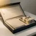 Premium-Onboarding-Box auf weißem Schreibtisch mit Willkommenskarte, Notizbuch, Stift und verpacktem Geschenk im warmen Goldlicht.