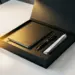 Geöffnete matte schwarze Onboarding-Box mit Notizbuch, Stift und gefalteten Dokumenten auf weißem Schreibtisch im warmen Licht.