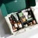 Offene Premium-PR-Box in smaragdgrün mit Goldakzenten enthält Lifestyle-Produkte in schwarzen Schaumstoff-Fächern
