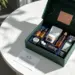 Offene Premium-PR-Box in Smaragdgrün mit roségoldenen Akzenten zeigt Lifestyle-Produkte in marineblauen Samtfächern